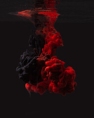 Red and black ink in water isolated on black background. Abstract background. Beautiful clouds of...