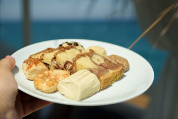 Beach vacation. A plate with sweets on the background of the sea and palm trees.