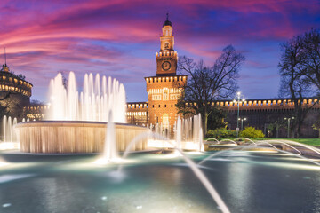 Fototapeta premium Sforza Castle with a fountain at night. Beautiful illumination of the building in warm colors. Milan Italy