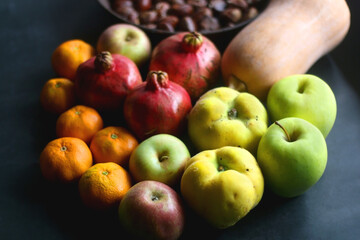 Pan with chestnuts, butternut squash and various fruit on dark background. Selective focus.
