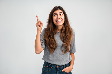 Wow, look up. Portrait of amazed woman pointing up to empty place on white background, expressing shock surprise and showing copy space for advertisement. Indoor studio shot