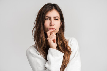 Hmm, i'm need thinking. Young woman looking at the camera, holding chin and musing. Indoor shot. Isolated on white background