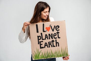 Caucasian brunette curly woman holding carton placard with I love planet Earth writing and looking...