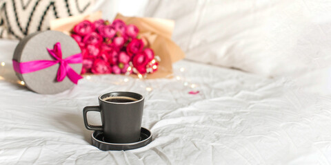 Cup of aromatic coffee gift and roses bouquet with fairy lights on bed banner