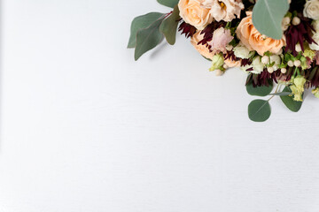 flowers and leaves on light white wooden background. blank for text