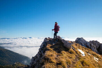 Woman on top of the mountain above the clouds bathing in sunlight.