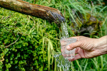 A man holds a glass under a fountain, from which still clean drinking water flows. By the year...