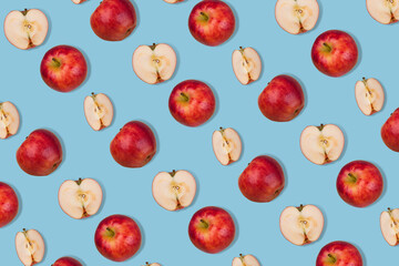 Trendy pattern of fresh whole apple and halves on  pastel blue background.