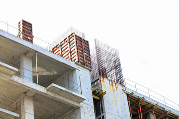Concrete construction of a new high-rise apartment building. An unfinished buildings facade view from outside. Residential complex exterior. Real estate investment. Slabs, walls without windows.