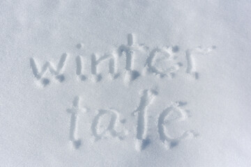 Inscription Winter tale, written on white background of the snow. Top view. Flat lay. Winter holiday. New year concept