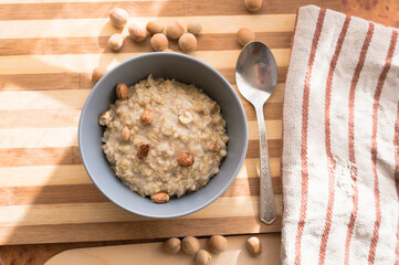 Healthy, dietary and nutritious oatmeal with hazelnuts in a gray plate on the table top view.