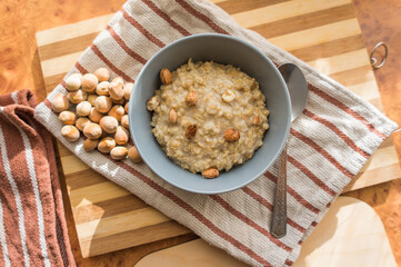 Healthy, dietary and nutritious oatmeal with hazelnuts in a gray plate on the table top view.