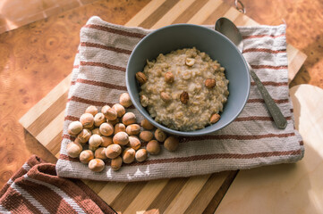 Healthy, dietary and nutritious oatmeal with hazelnuts in a gray plate on the table top view.