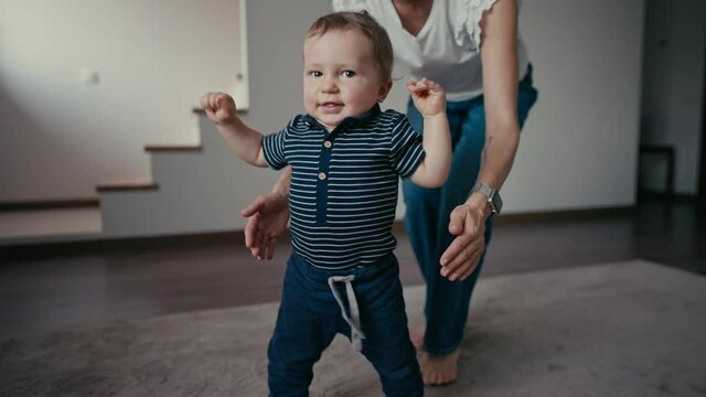 Cute smiling baby boy learning to walk. Baby's First Steps. Baby making his first steps