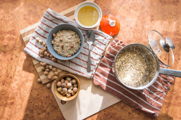 Healthy, dietary and nutritious oatmeal with delicious homemade honey, hazelnuts in a gray plate on the table top view.
