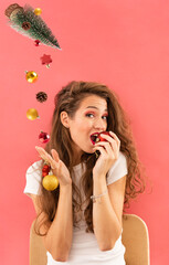 Beautiful woman with Christmas bauble decoration. Christmas decoration falling dowm from Christmas tree in her hand.