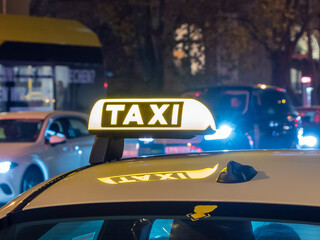 Night photograph of a taxi car. Taxi sign on the car roof glows in the dar