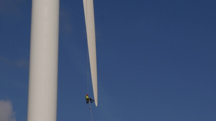 Man in Harness abseiling at tip of Wind Turbine blade, undergoing maintenance, Highest Commercial...