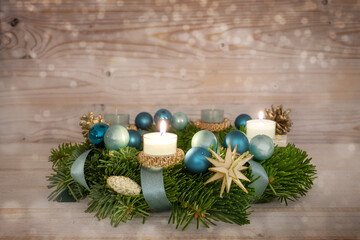 Advent wreath series number two with lit candles, blue Christmas baubles and decoration on a rustic...