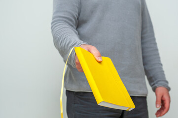Close-up at male holding a yellow book in his hands.