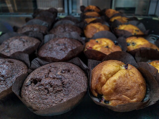 Vanilla and chocolate muffins in brown paper on a cafe shop window showcase, concept 