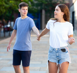 Obraz premium Two teenagers are walking hand in hand in summertime