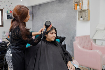 Stylist drying her client's hair in beauty salon - Professional hairdresser working with client in salon - Enterprising professional woman