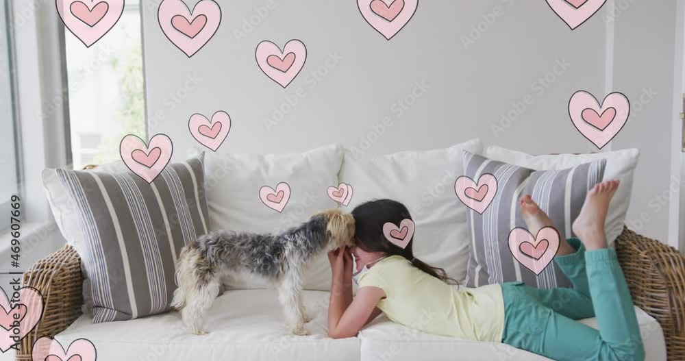 Canvas Prints Animation of hearts moving over caucasian girl wearing face mask playing with her pet dog