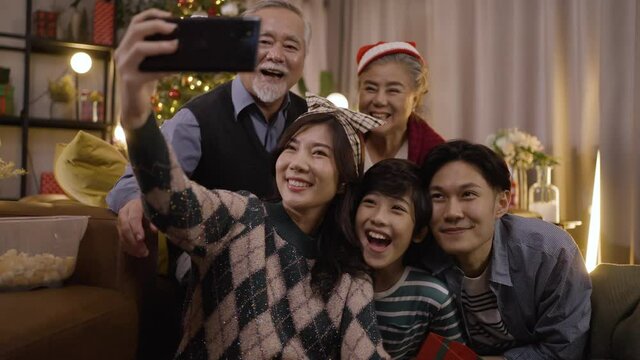 Asian family taking selfie near Christmas tree together at home. Family, holidays, Christmas concept