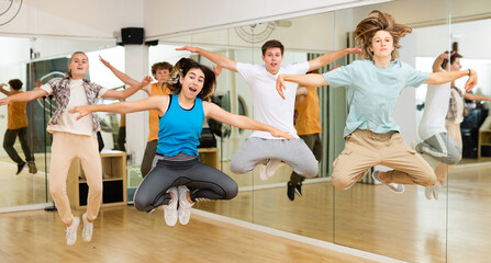 Group of teenagers jumping together during dance class in studio.