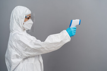 doctor in protective PPE suit scanning with infrared thermometer
