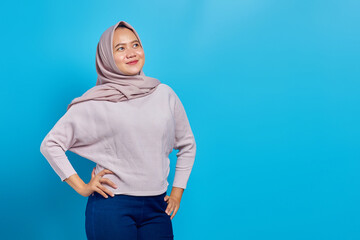 Cheerful Asian woman looking aside over blue background