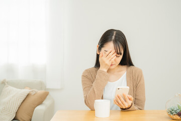 スマホを見てショックを受ける女性
