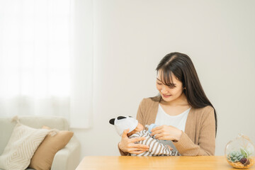 哺乳瓶で赤ちゃんにミルクを飲ませる女性（笑顔）
