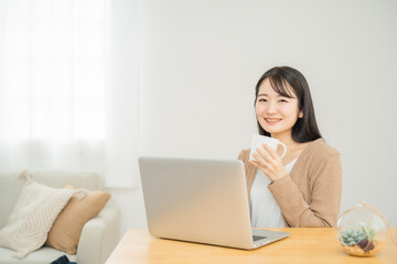 家でノートパソコンを使う女性（飲み物）
