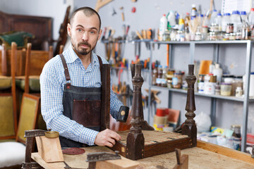 Concentrated craftsman using carpentry tools for restoration old armchair in workshop