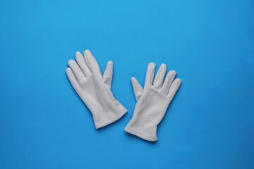 Warm fleece women's gloves on a blue background. Flat lay.