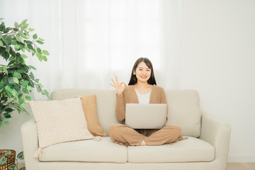 家でノートパソコンを使う女性（ソファ）
