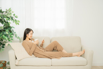 ソファでスマホを使う女性（笑顔）
