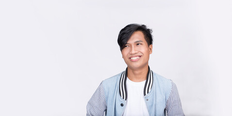 An attractive Filipino man in a varsity jacket looks up to his side while smiling. Boy next door...