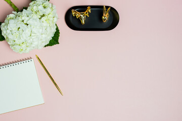 A notebook with white hydrangeas and golden animals over the pink background. 