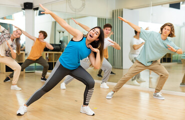 Naklejka na ściany i meble Group of positive teenagers dancing modern dance in ballroom.