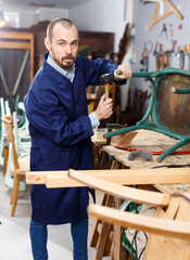 Concentrated craftsman using carpentry tools for restoration old armchair in workshop