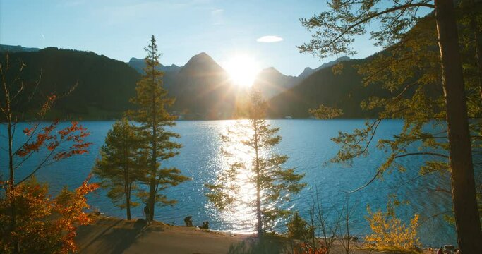 Men smoking sitting near trail by scenic view of alps mountains at lake achensee in sunset golden hour in Austria, Europe. Wide Angle.