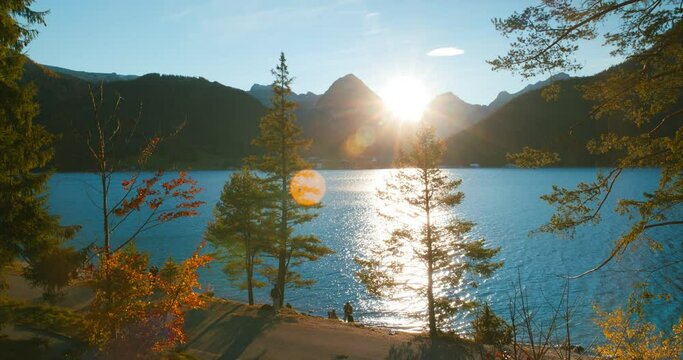 A group smoking near walking trail by scenic view of alps mountains at lake achensee in sunset golden hour in Austria, Europe. Wide Angle.