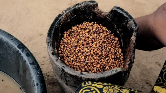 An African motor and pestle being used to pound and grind tiger nut into flour - isolated close up