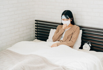 ベッドで休む体調不良の女性（冷却シート・咳・マスク）
