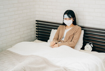 ベッドで休む体調不良の女性（冷却シート・マスク）
