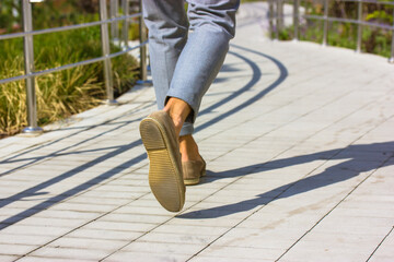 Feet of pedestrian businessman. Man in gray pants, brown shoes walking on big city street at sunny...