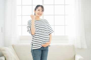 部屋にいる妊婦（笑顔・ガッツポーズ）
